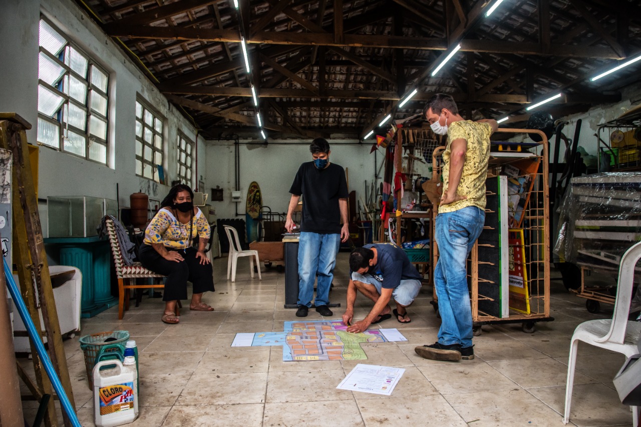 Equipe em volta do mapa no chão da oficina